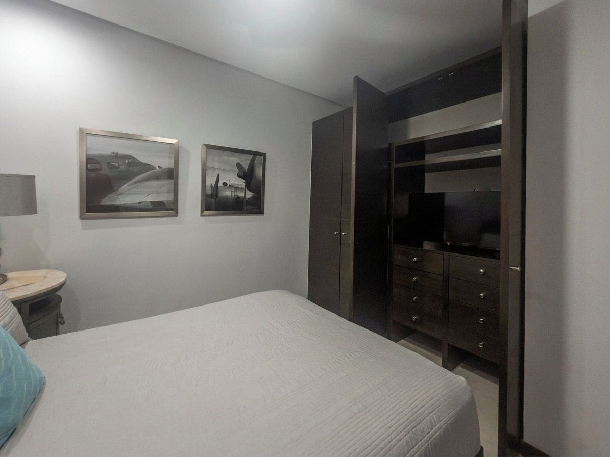 Un dormitorio con cama, cómoda, espejo y armario.