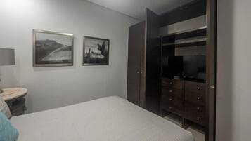 Un dormitorio con cama, cómoda, espejo y armario.