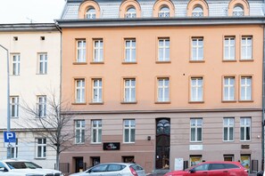 En bygning med flere etager, en flad facade, adskillige vinduer og en indgang i stueplan.