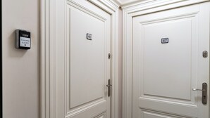Duas portas brancas com os números 46 e 47, um interfone e um teclado na parede.