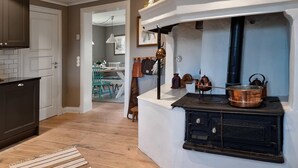 A kitchen with a built-in stove, wooden cabinets, and a dining area with a table and chairs. - Cozy home in Väby with WiFi (Väby)