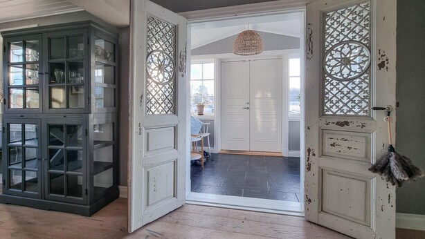 A room with a dark wooden cabinet, a white door with decorative glass panels, and a hanging broom. - Cozy home in Väby with WiFi (Väby)
