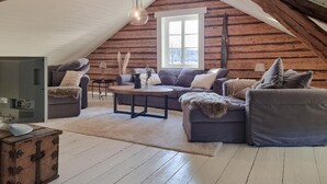 A cozy loft-style living room with a wooden sloped ceiling, a large window, and a rustic aesthetic. - Cozy home in Väby with WiFi (Väby)