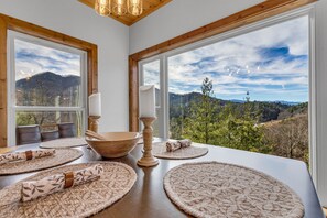 A dining area with a table set for four, large windows offering a view of a mountainous landscape. - Epic Mountain Views-Wears Valley-Hot Tub-Dollywood-Family Fun! (Sevierville)