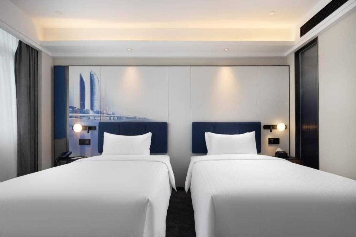 Une chambre d’hôtel avec deux lits, une vue sur la ville et un design moderne.