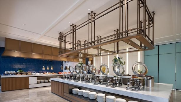 A modern kitchen with a buffet setup, featuring stainless steel appliances and a variety of food items. - Hampton by Hilton Xiamen Tong'an Chengnan (Xiamen)