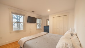 A bedroom with a bed, a dresser, a TV mounted on the wall, and a closet. - World Cup ready. with AC, beaches, Boston, and Salem (Melrose)
