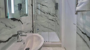 A modern bathroom with a marble vanity, a glass shower enclosure, and a walk-in shower. - Kings Cross 1 Bedroom Apartment (London)