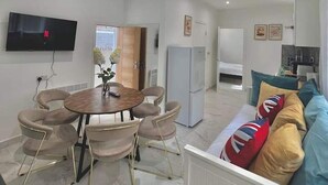 A modern living room with a dining area, a kitchen, and a TV mounted on the wall. - Kings Cross 1 Bedroom Apartment (London)
