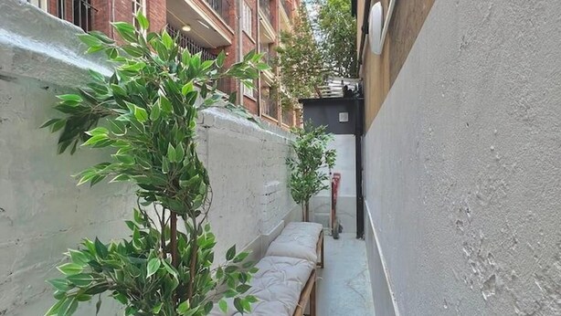 A narrow alleyway with a row of wooden benches and potted plants. - Kings Cross 1 Bedroom Apartment (London)
