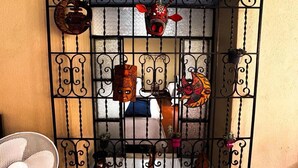 A room with a barred window, a fan, and various decorative items including masks and a small plant. - Casita Sol (Antigua Guatemala)