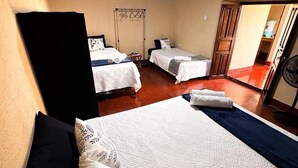 A hotel room with a large bed, two smaller beds, a wardrobe, and a ceiling fan. - Casita Sol (Antigua Guatemala)