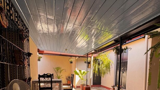 A spacious room with a high ceiling, a fan, a table with stools, and potted plants. - Casita Sol (Antigua Guatemala)