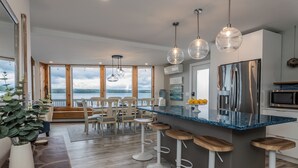 Een moderne keuken met een groot eiland, barstoelen en uitzicht op het meer.
