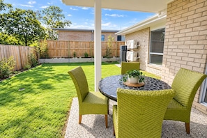 A patio with a round table and four chairs, a potted plant, and a brick wall. - Serene 4-bedroom house with AC in charming Park Ridge (Park Ridge)