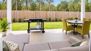 Un espacio de estar al aire libre cubierto con sofá, sillas, una mesa y una parrilla.