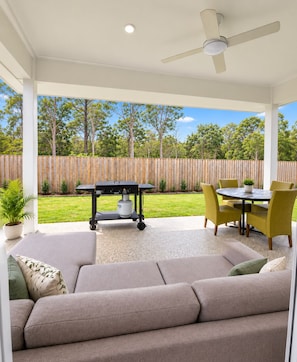 A covered outdoor seating area with a sofa, chairs, a table, and a barbecue grill. - Serene 4-bedroom house with AC in charming Park Ridge (Park Ridge)