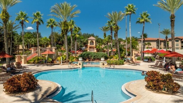 A swimming pool surrounded by palm trees and lounge chairs. - Disney escape 4BR Townhome + Resort (Davenport)