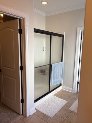 A hallway with a glass shower door, a white door, and a white rug on the floor. - Perfect Masters Rental - 5-bedroom/3.5 bath home in Evans. Easy commute to ANGC (Evans)