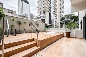 Zona exterior moderna amb escales de fusta, barana metàl·lica i plantes en testos.