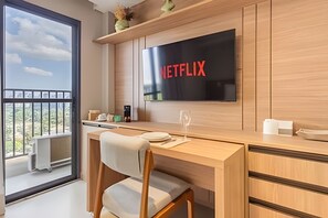 Una cuina moderna amb televisió integrada que mostra 'NETFLIX', taula de dinar de fusta, una cadira i un balcó amb vistes.