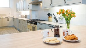 Een moderne keuken met witte kastjes, een fornuis en een koffiezetapparaat op het aanrecht.