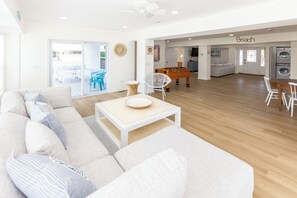 Uma sala de estar ampla com um sofá, uma mesa de centro e uma mesa de pebolim.