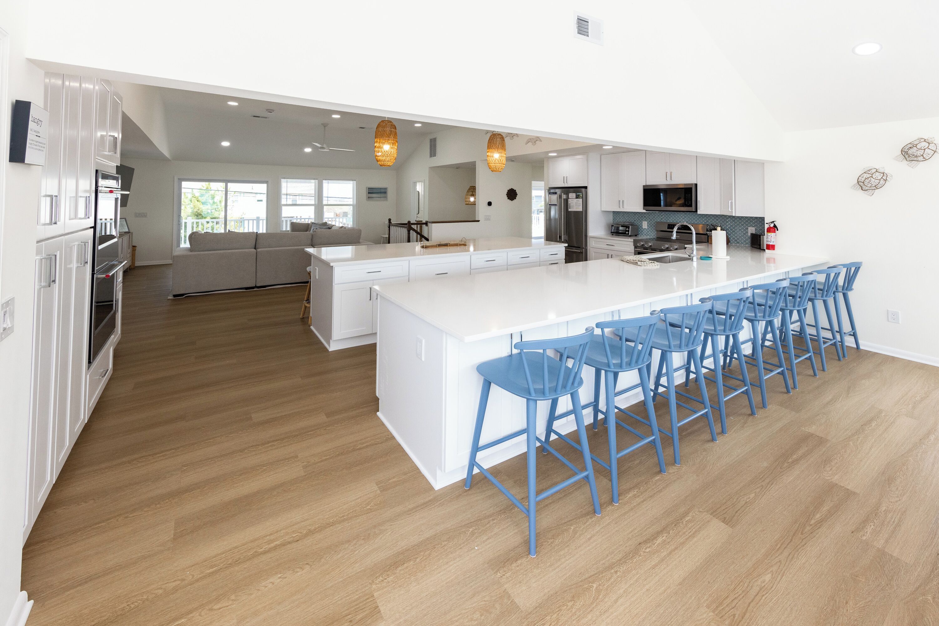 A modern kitchen with a large island, bar stools, and a view to the living area.