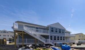 A two-story building with a balcony on the upper floor, a staircase leading to the balcony, and construction materials on the ground. - SEASIDE RETREAT - 8 bedroom semi-oceanfront with pool and ocean views (Virginia Beach)