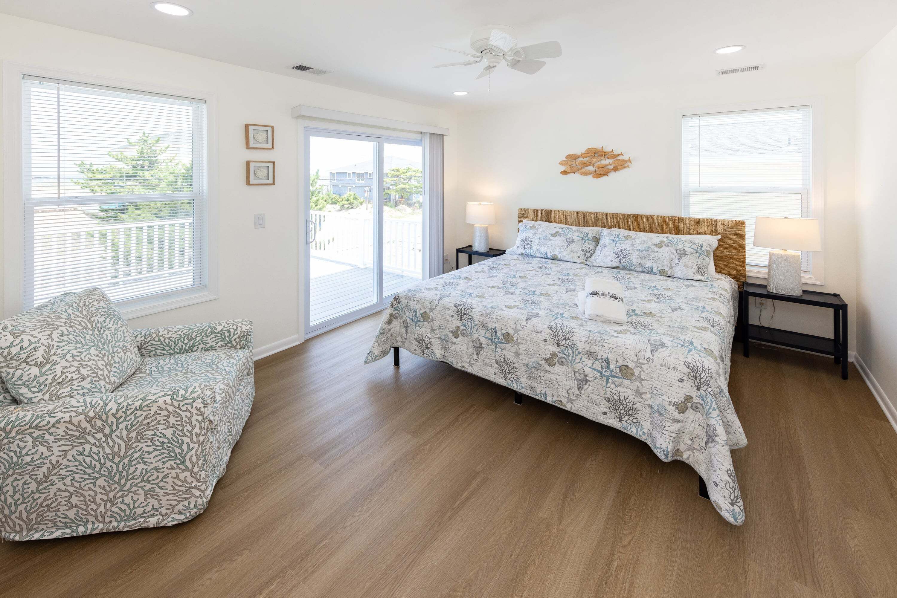 A bedroom with a bed, a chair, a ceiling fan, and a view through the window.
