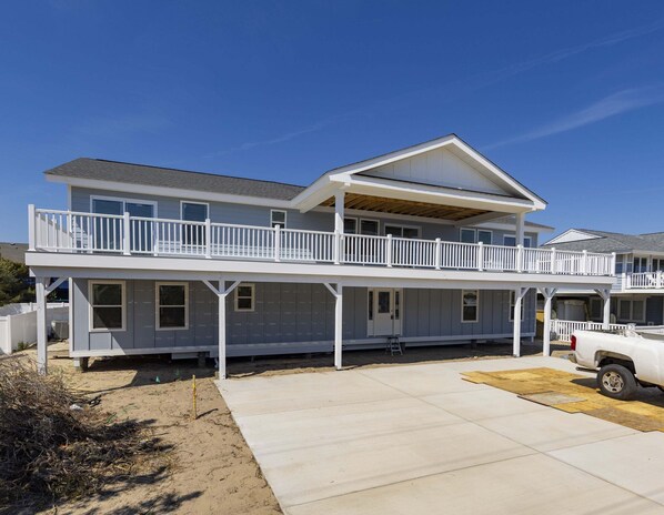 A two-story house with a covered porch and a garage. - SEASIDE RETREAT - 8 bedroom semi-oceanfront with pool and ocean views (Virginia Beach)