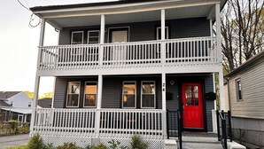 A two-story house with a red door, white railings, and a number '24' on the front.
