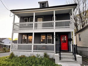 A two-story house with a red door, white railings, and a number '24' on the front. - Spacious 4-bedroom apartment 25 min to NYC & 10 min to EWR (Union)