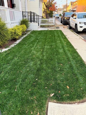 A well-maintained lawn with a white picket fence, a small tree, and a sidewalk. - Spacious 4-bedroom apartment 25 min to NYC & 10 min to EWR (Union)