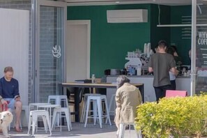 An outdoor seating area with tables and chairs, a counter with a person behind it, and a dog nearby. - Contemporary 2BR Apartment | Heart of Prospect (Prospect)