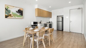 Een moderne keuken met houten kastjes, een eettafel voor vier personen en een magnetron.