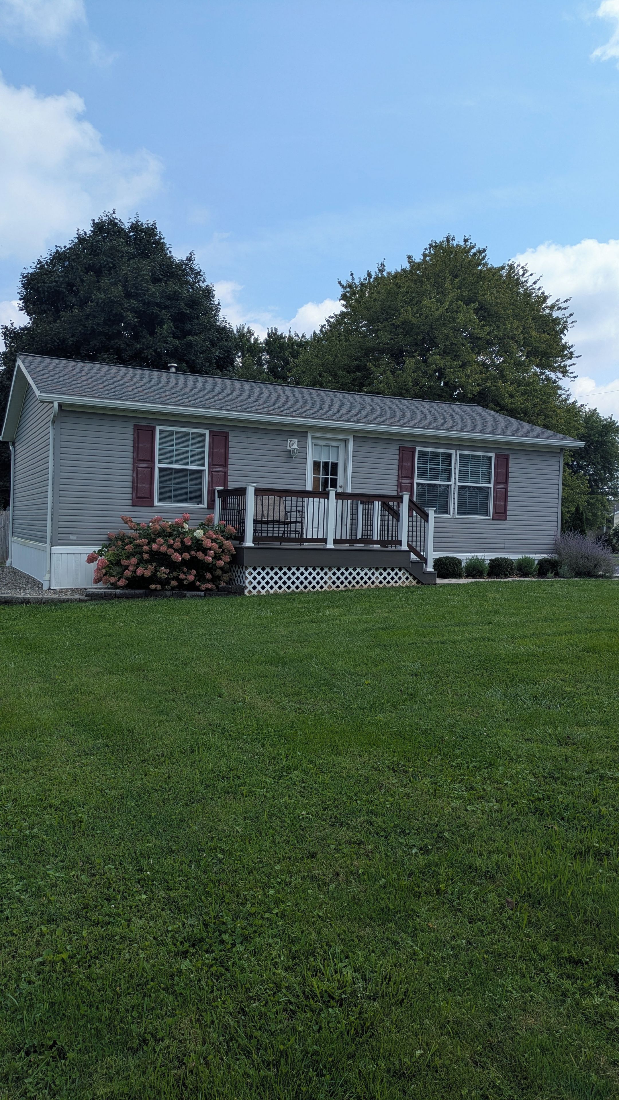 A single-story house with a front porch, a small deck, and a well-maintained lawn.
