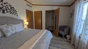 Ein Hotelzimmer mit einem großen Bett, einem Sessel, einem Kleiderschrank und einem durch eine offene Tür einsehbaren Badezimmer.