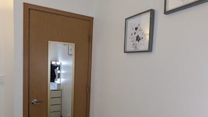 Ein Flur mit einer Holztür, einem beleuchteten Spiegel und zwei gerahmten Bildern an der Wand.