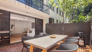 Une terrasse extérieure avec une table à manger, des chaises et un barbecue.