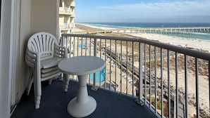 Ein Balkon mit Tisch und Stühlen mit Blick auf Strand und Steg.
