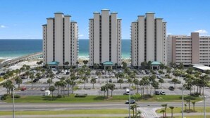 Ein Strandhotel mit drei hohen Gebäuden, einem Parkplatz und Blick auf den Ozean.