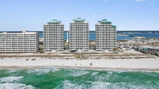 Ein Hotel direkt am Strand mit drei Hochhäusern, einem Sandstrand und dem Meer.