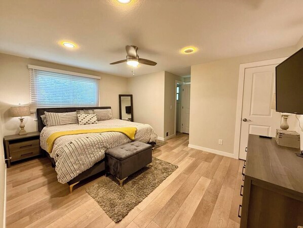 Ein Schlafzimmer mit Bett, Nachttisch, Lampe und Deckenventilator.