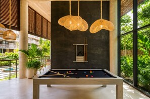 A pool table with balls, a hanging light fixture, and a view of greenery outside. - Tulum Premium Maisonette | Jacuzzi & Cenote (Tulum)