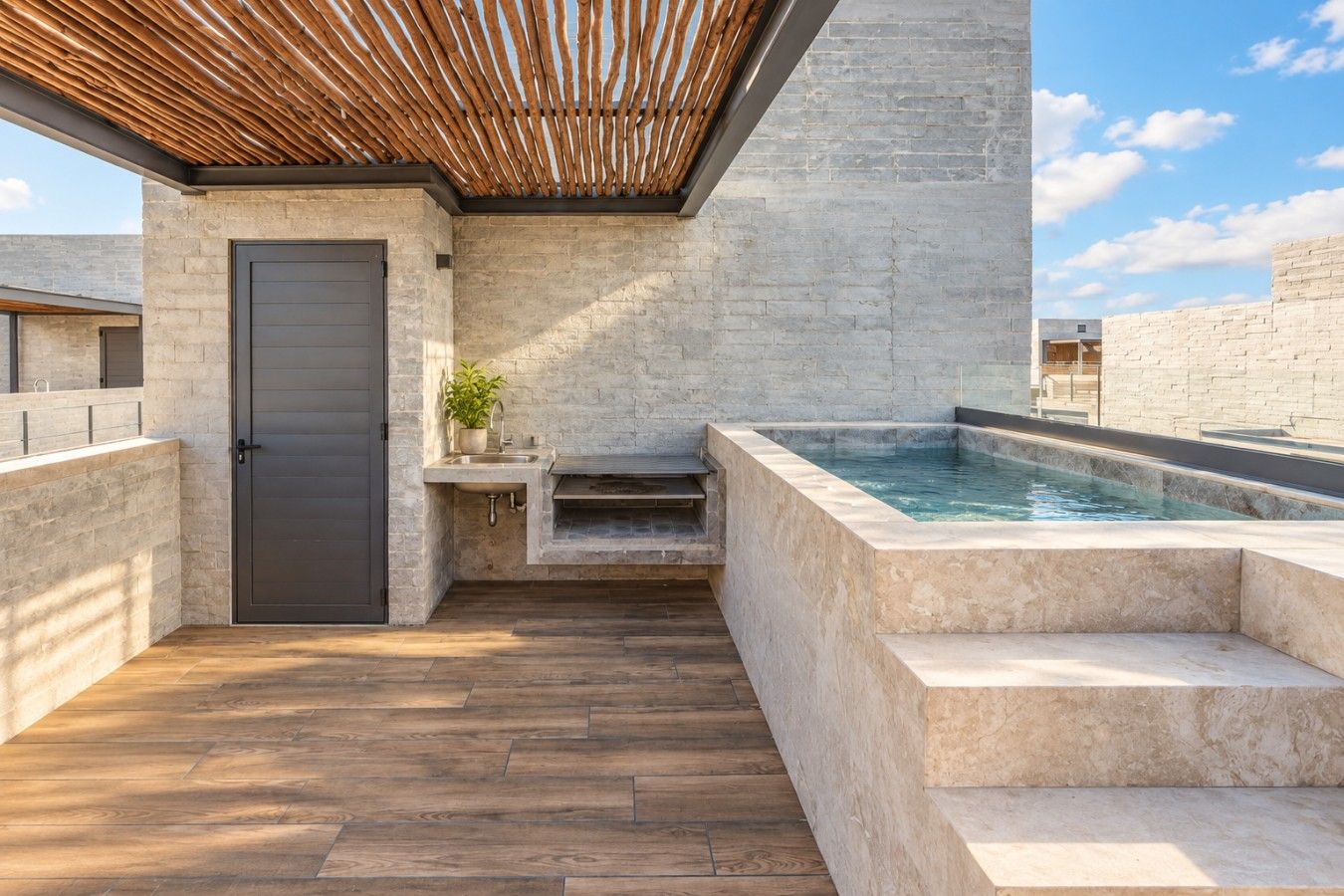Ein modernes Badezimmer im Freien mit Steinsandsteinwand, Holzboden, eingebautem Waschbecken und Whirlpool.