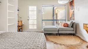 A bedroom with a bed, a grey sofa, a large window, and a door. - Cozy Private Suite • 10 Min to SoFi/Intuit/LAX/Manhattan & Venice Beach (Inglewood)