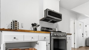 Une cuisine moderne avec des meubles blancs, un four encastré et un four à micro-ondes.