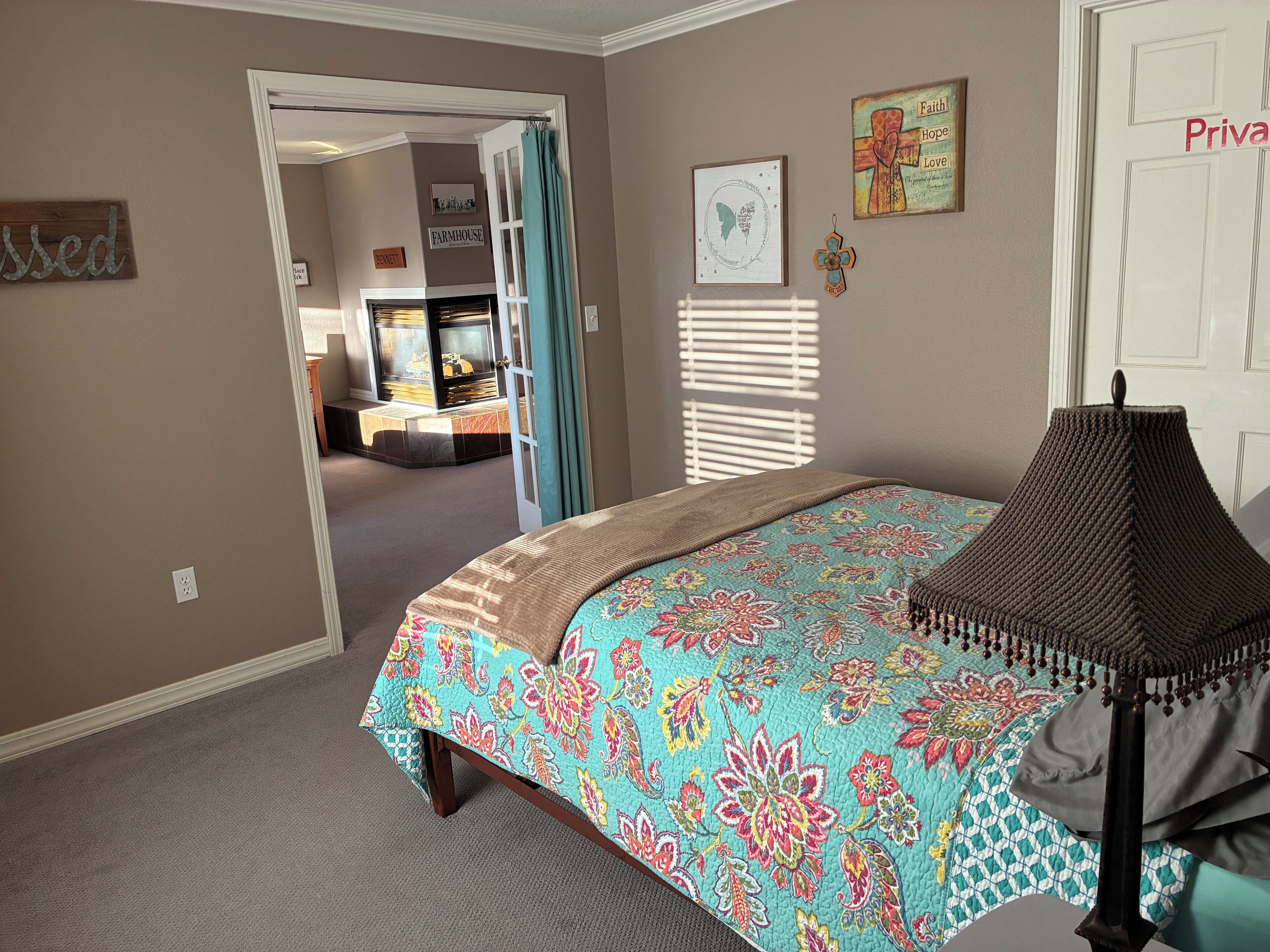 A bedroom with a bed, a nightstand, a lamp, and a door with a privacy sign.