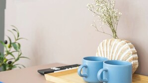 A wooden tray with two blue mugs and a seashell vase with white flowers. - Cabanyal Rooms by VLC Host 1 (Valencia)